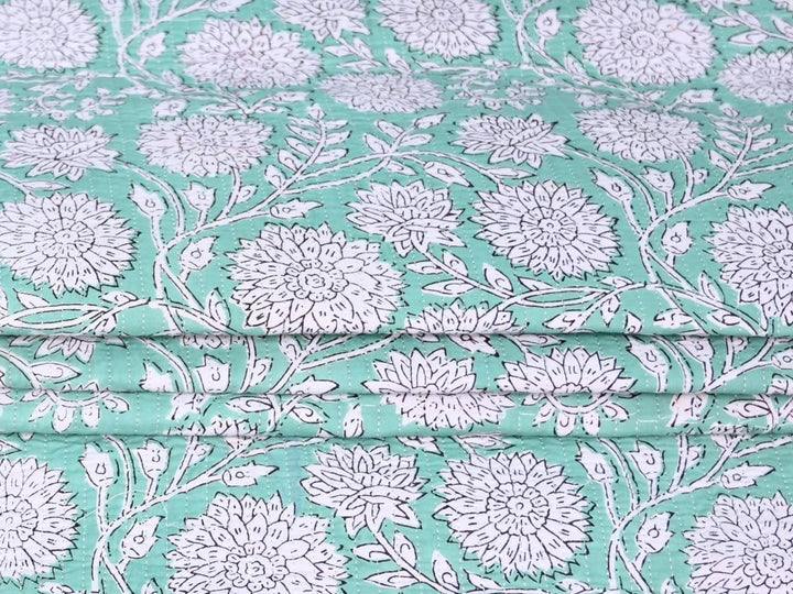 Mint quilted cotton fabric showing chrysanthemum-style white flowers and vines