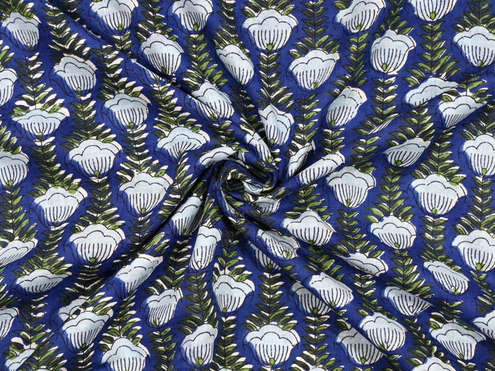 Close-up of cobalt blue cotton fabric with detailed white linework and olive green leaf details
