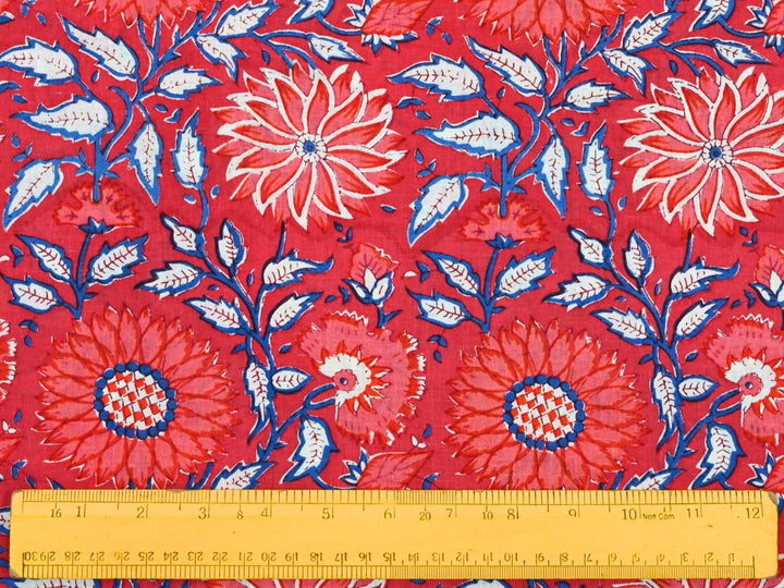 Close-up of red floral cotton fabric with blue leafy stems and white veining