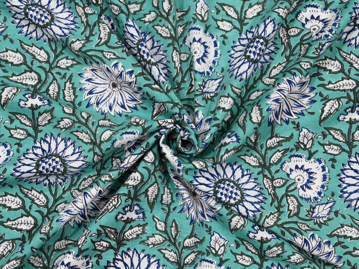 Seafoam green cotton fabric showing white and blue chrysanthemum flowers