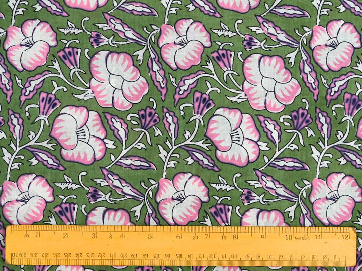 Green cotton fabric showing pink and white flowers with purple accents