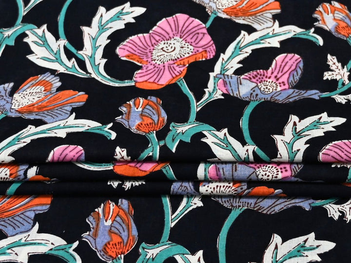 Black cotton fabric showing pink, lavender, and orange poppy blooms