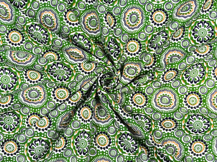 Green cotton fabric showing black and white medallions with orange accents
