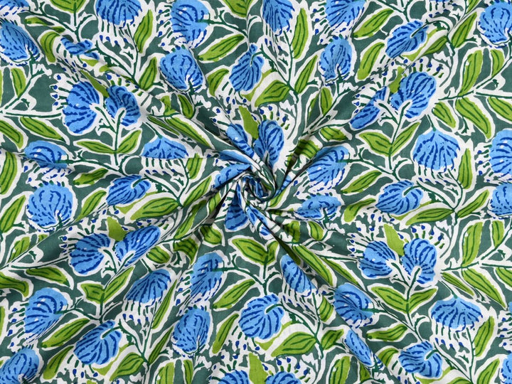 Deep green cotton fabric showing cornflower blue blooms with lime green leaves