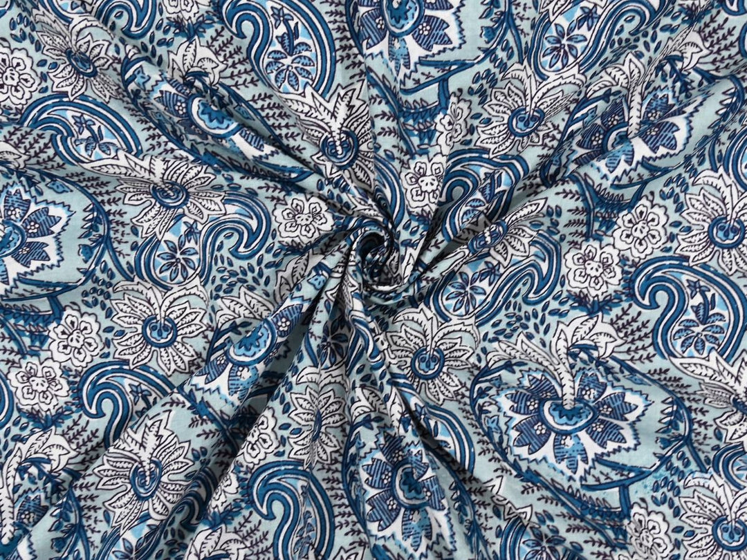 Light blue cotton fabric showing navy paisley motifs with white florals