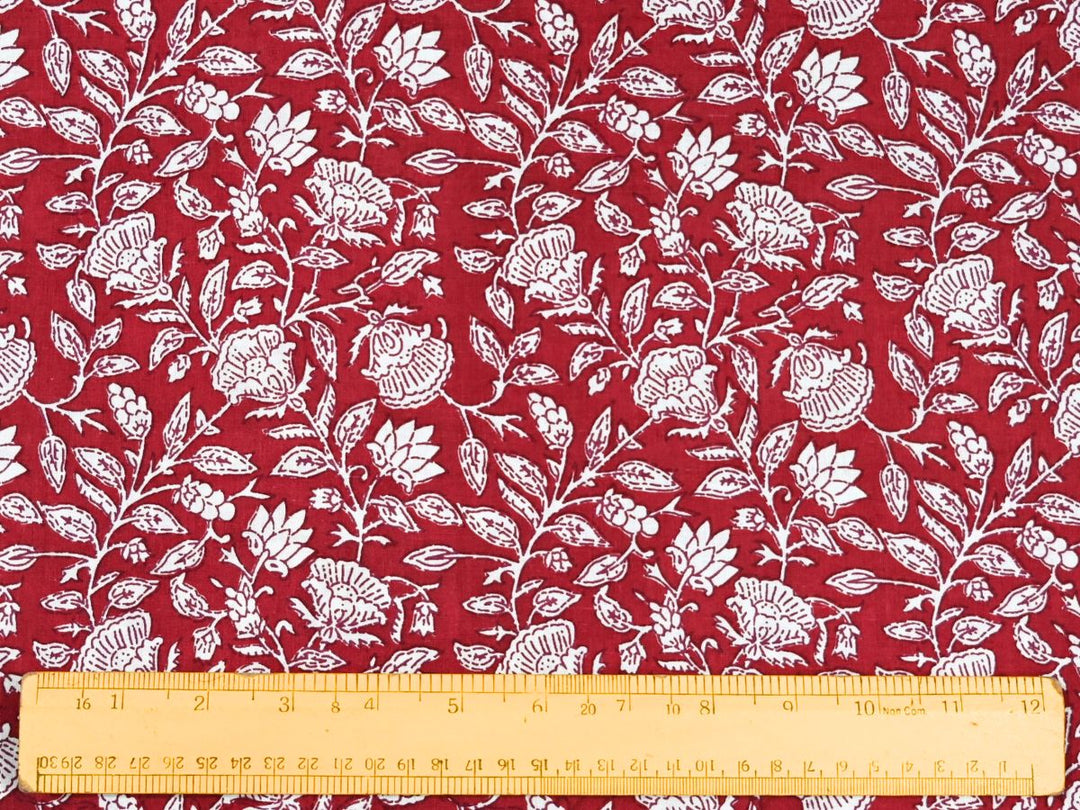 Close-up of red and white cotton fabric with detailed linework and vine details