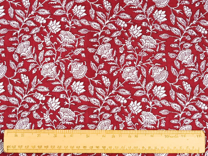 Close-up of red and white cotton fabric with detailed linework and vine details