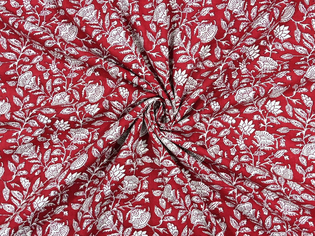 Deep red cotton fabric showing white rose and lotus motifs with leafy vines
