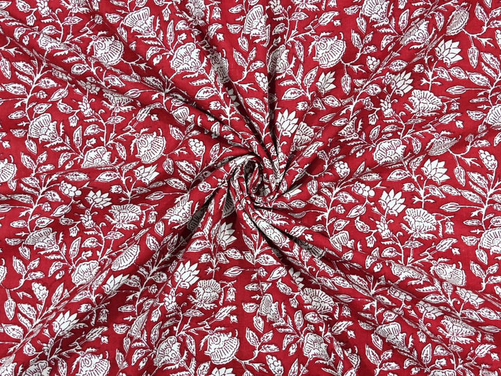 Deep red cotton fabric showing white rose and lotus motifs with leafy vines