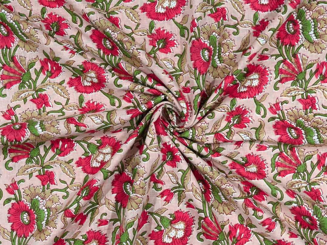 Blush pink cotton fabric showing vivid red blooms with green foliage