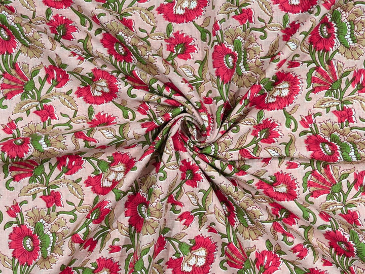 Blush pink cotton fabric showing vivid red blooms with green foliage