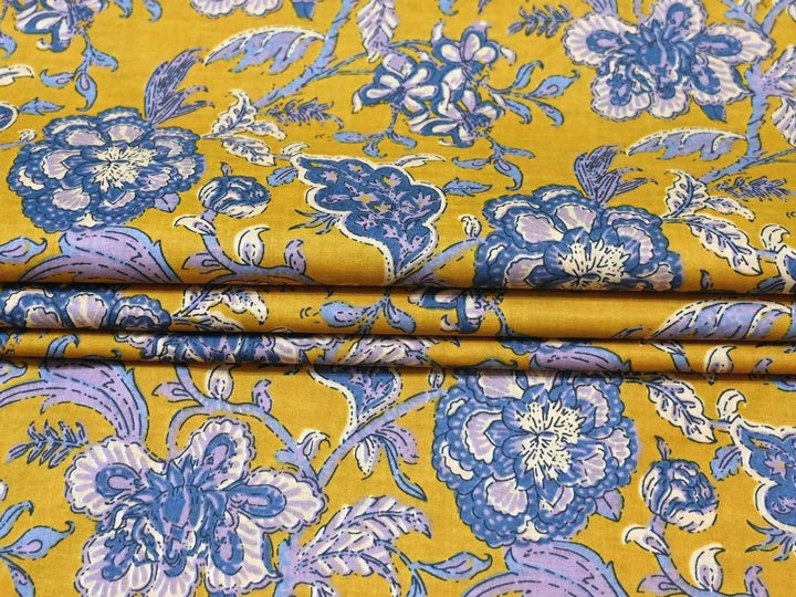 Large-scale floral block print fabric with blue leafy stems on yellow