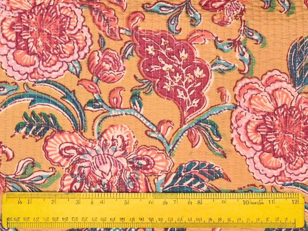 Close-up of mustard quilted floral fabric with teal dotted leaf details