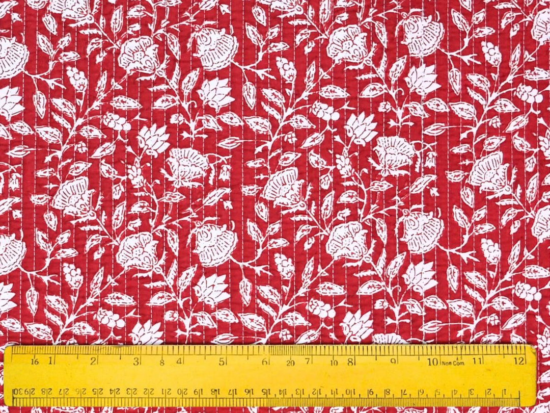 Red quilted cotton fabric showing white rosette and lotus flower motifs
