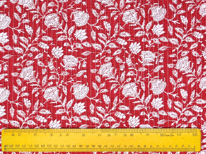 Red quilted cotton fabric showing white rosette and lotus flower motifs