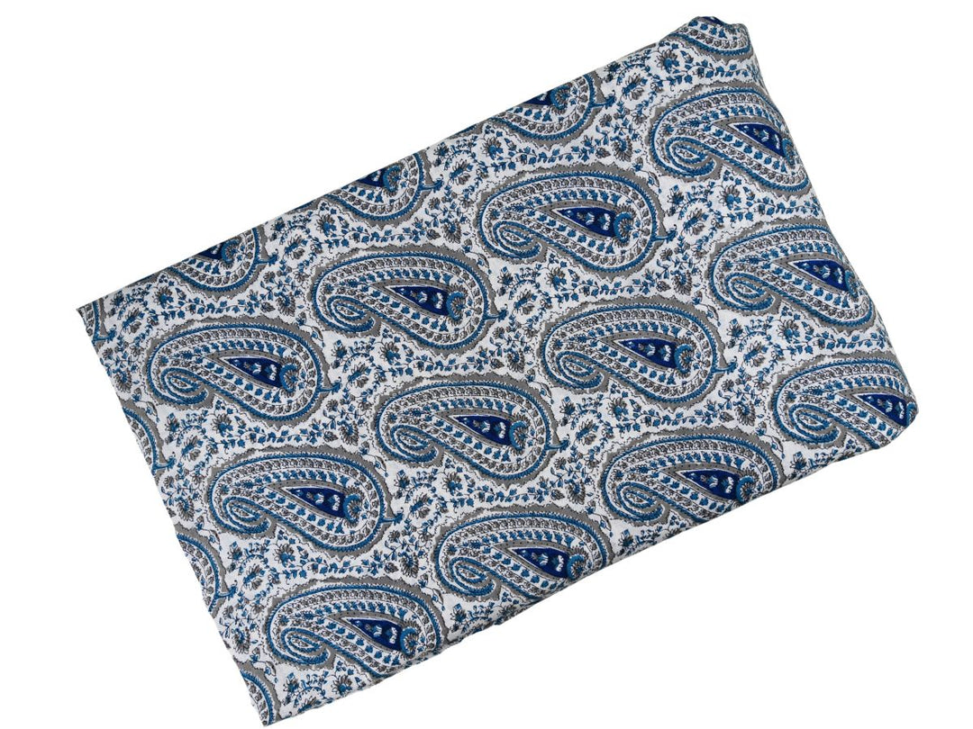 White cotton fabric showing navy blue paisley motifs with teal leafy vines