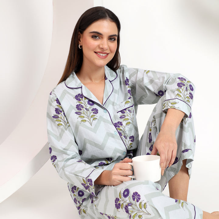 sitting and showing the off-white cotton pj set with lavender floral print and stylish lapel collar.