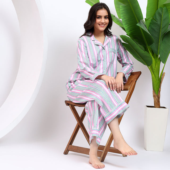 Sitting on chair view of the pink striped pajama set, featuring a cozy top and matching pants.