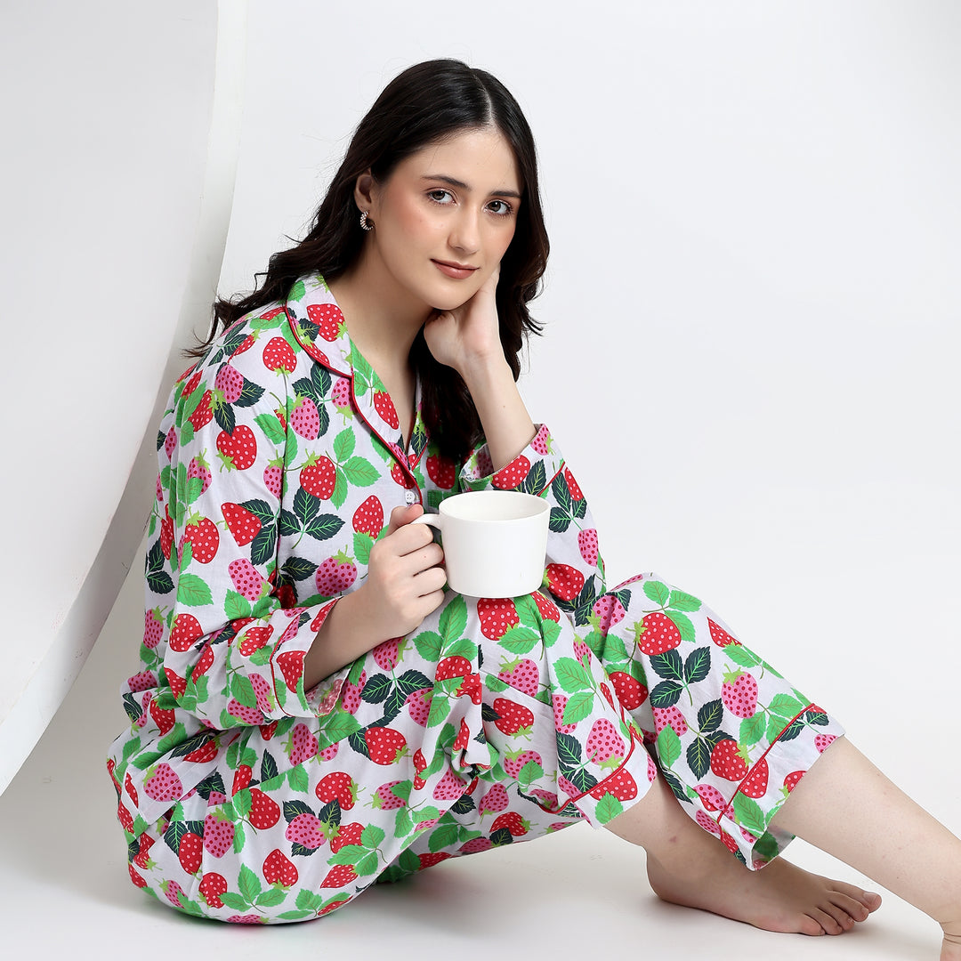 Sitting view showing side pockets of white cotton pajama set with pink-red strawberry print for a cozy, stylish look.