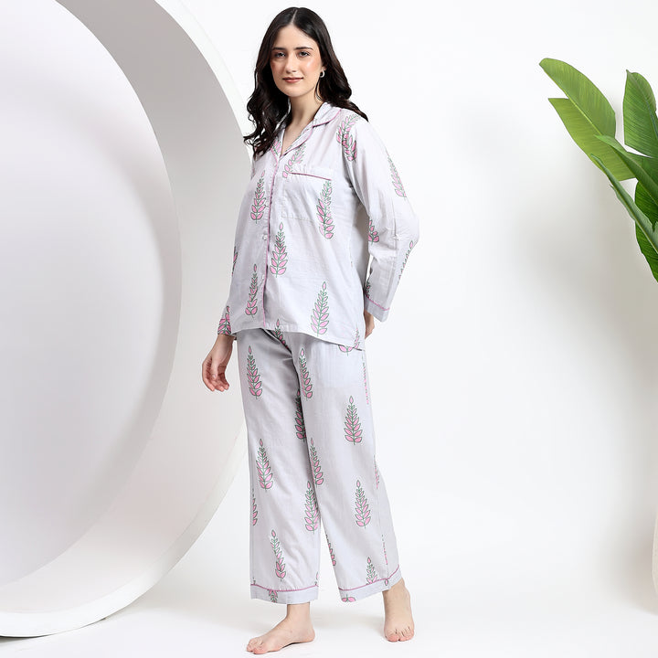 Leaning on the wall view of white cotton pajama set with floral print, featuring a lapel collar and relaxed fit for ultimate comfort.